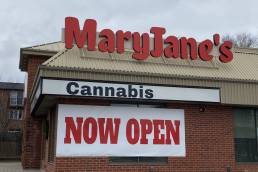 Signs on a brick building say Maryjane's Cannabis Now Open