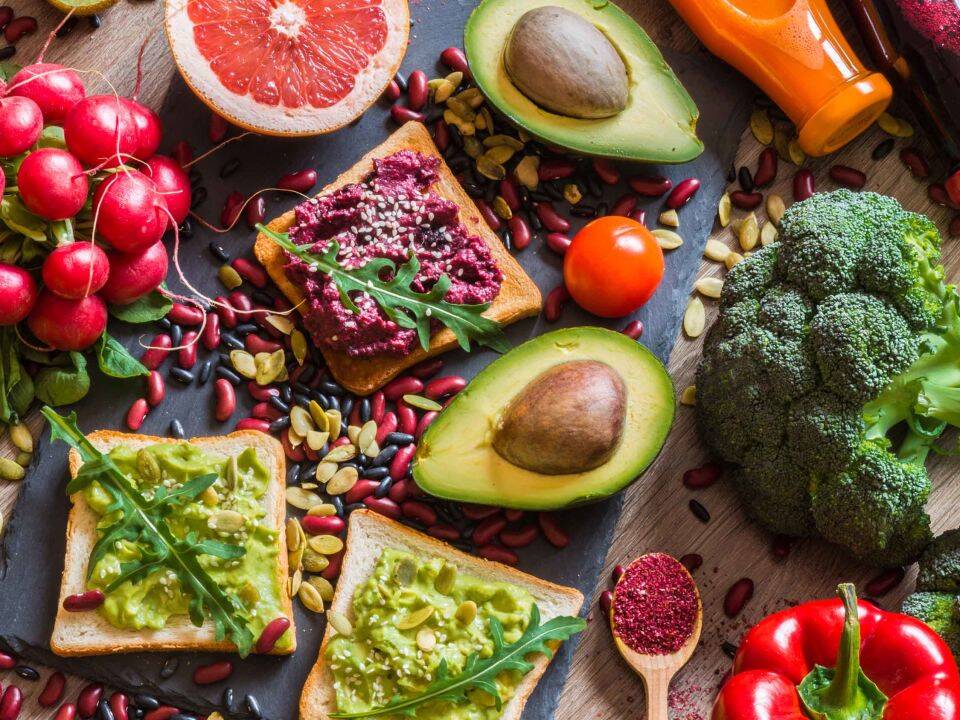 a variety of plant-based food such as avocados, grapefruit, bread, and lots of veggies. as