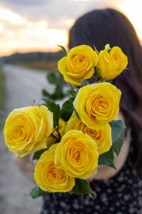 Girl holding yellow flowers showing the camera.