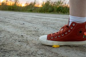 Someone else accidentally stepping on the fallen flower in the dirt.