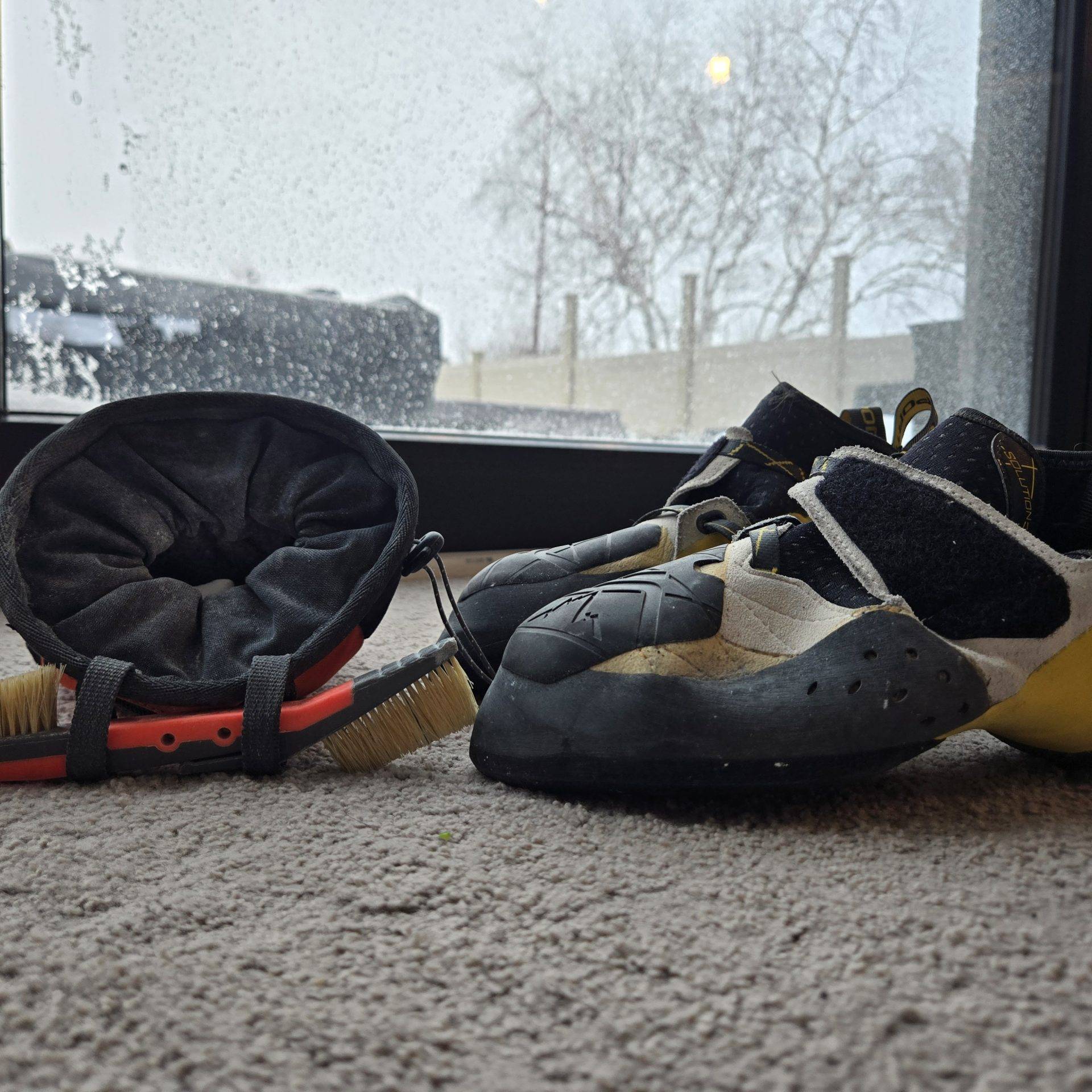 A chalk bag, brush, and rock climbing shoes.