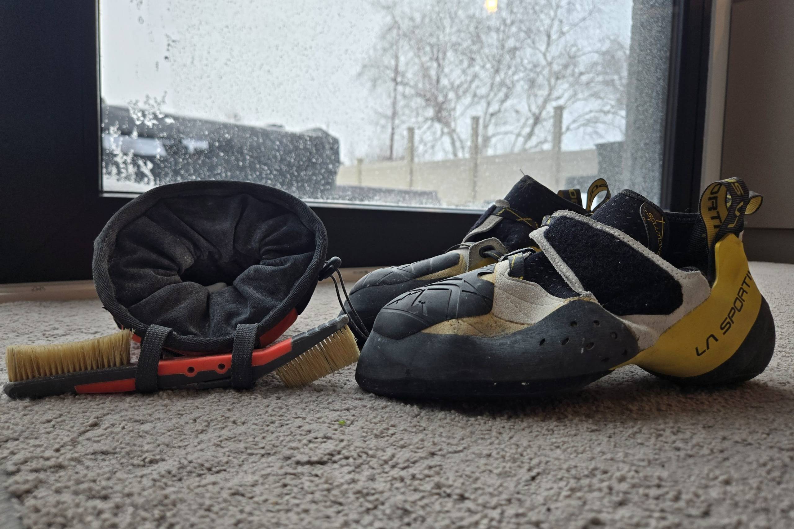 A chalk bag, brush, and rock climbing shoes.