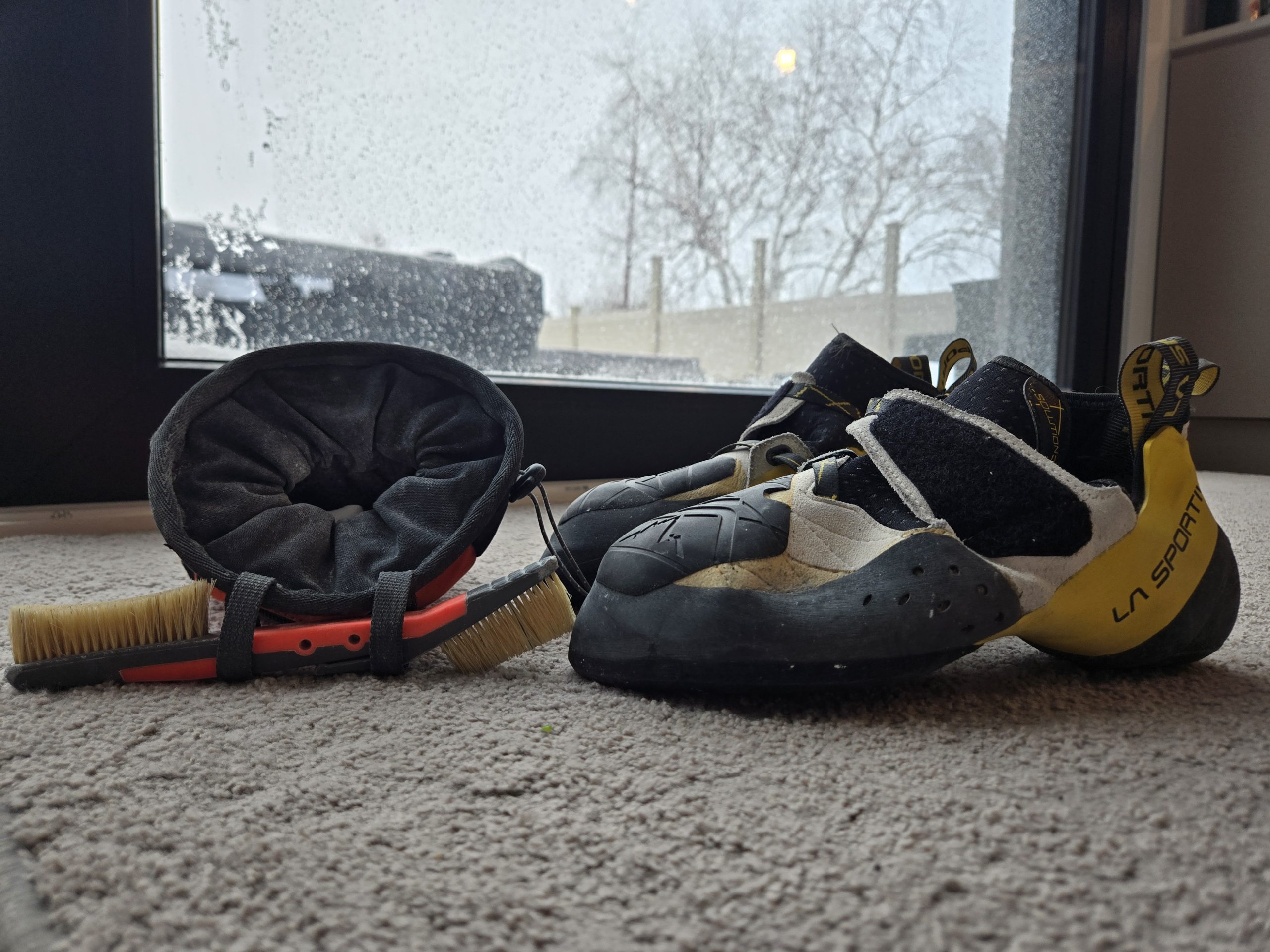 A chalk bag, brush, and rock climbing shoes.